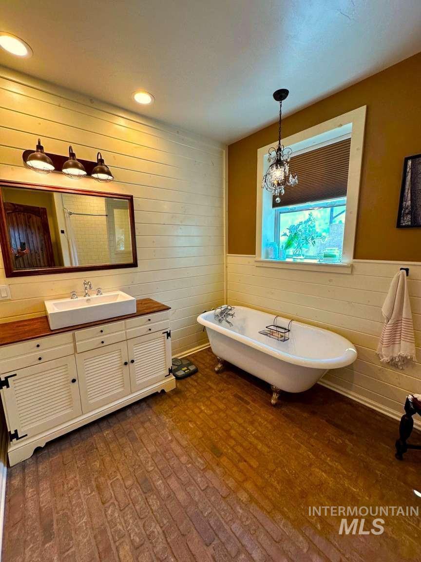 Bathroom with wooden walls, a freestanding bath, vanity, a wainscoted wall, and recessed lighting