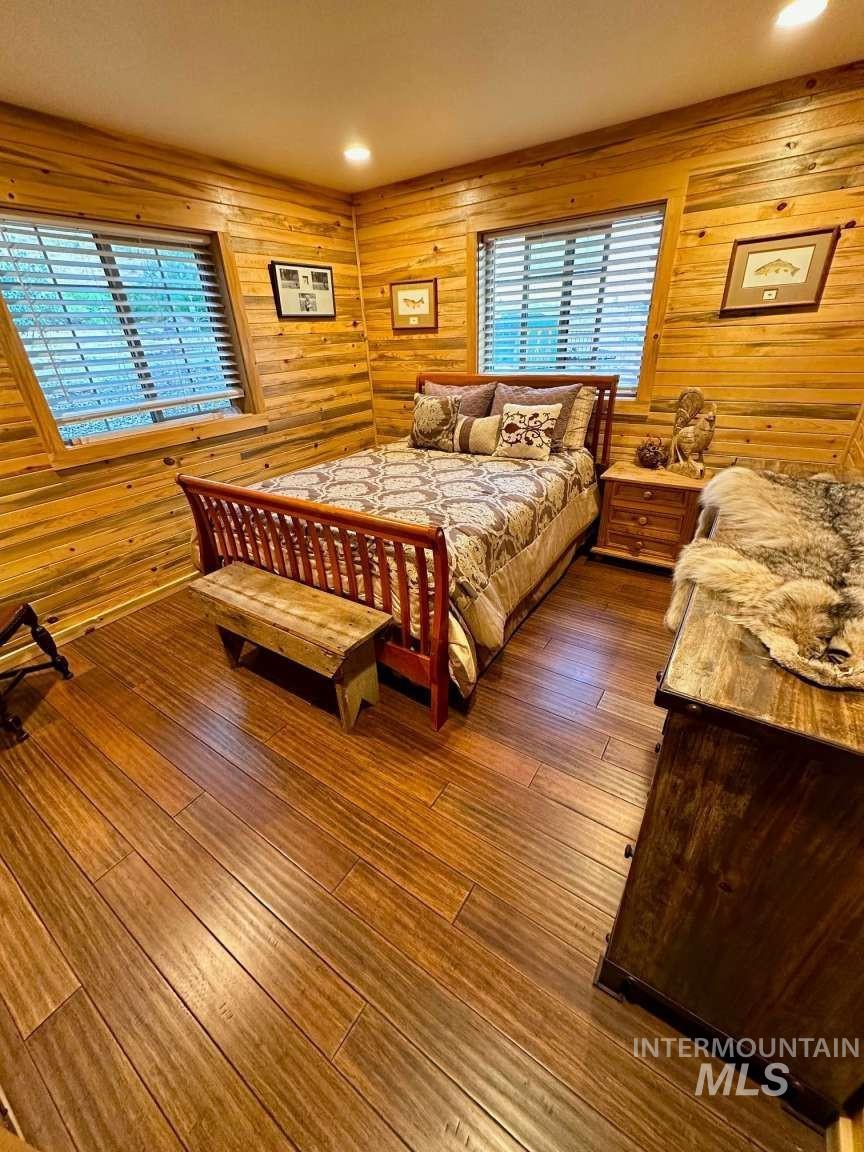 Bedroom featuring wood walls, dark wood-type flooring, and recessed lighting