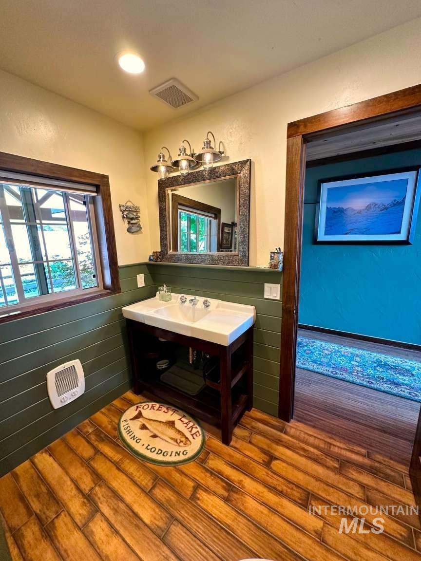 Bathroom featuring vanity, wainscoting, and dark wood-style floors