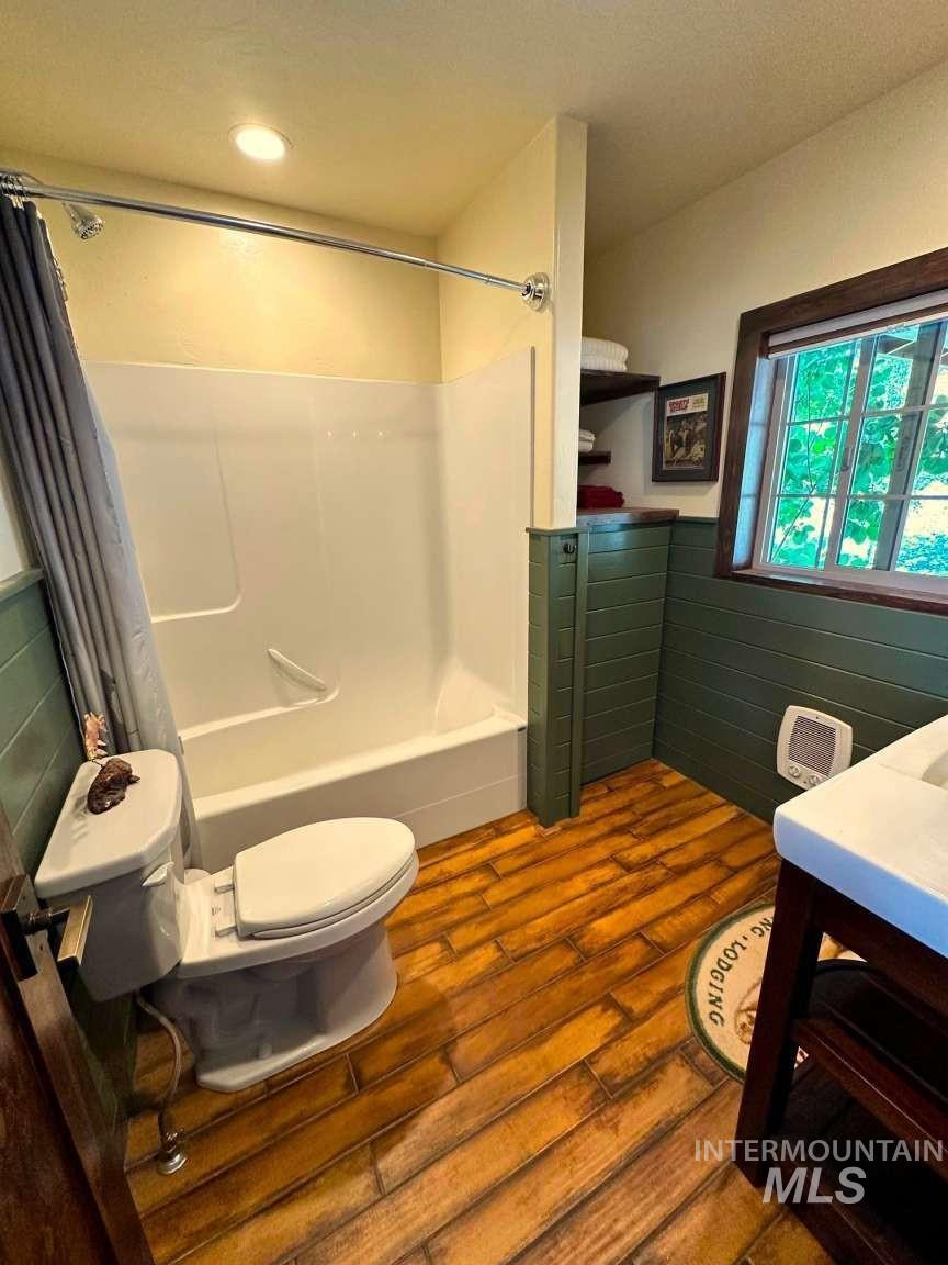 Full bathroom featuring shower / tub combo, vanity, dark wood-type flooring, and wainscoting