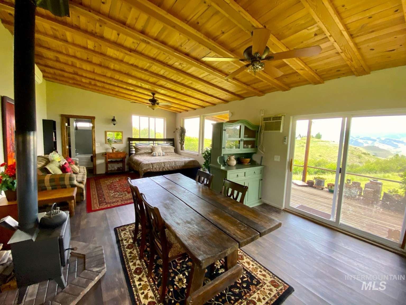 Dining room with a wood stove, dark wood finished floors, wood ceiling, a ceiling fan, and a wall mounted air conditioner