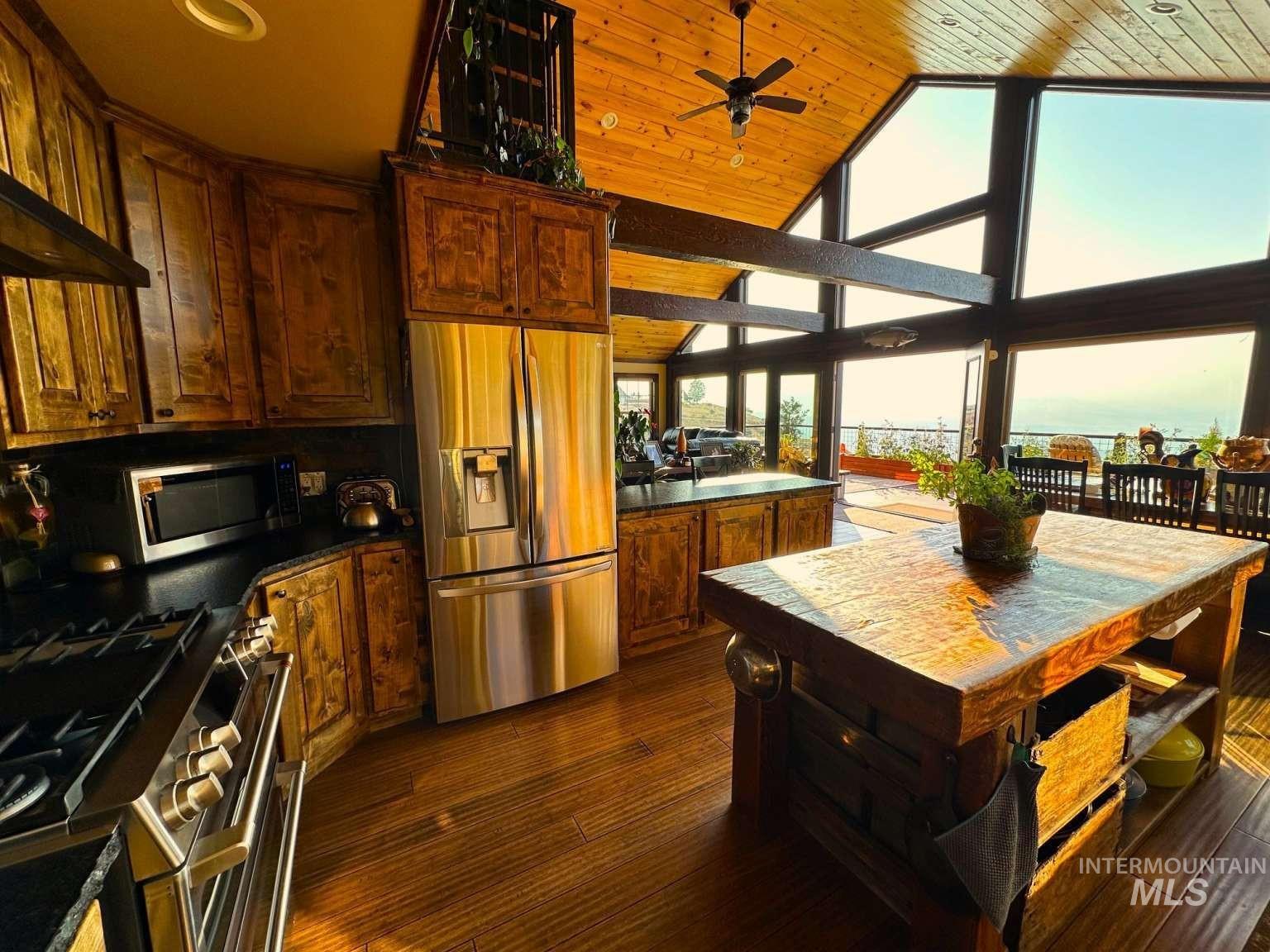 Kitchen with appliances with stainless steel finishes, high vaulted ceiling, dark wood-style flooring, a ceiling fan, and wooden ceiling