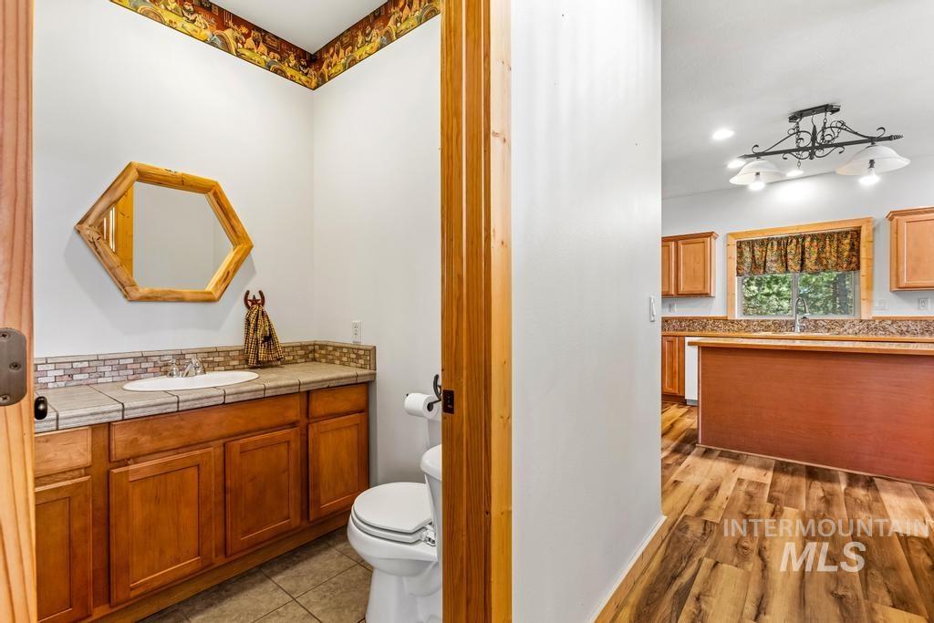 Half bath with decorative backsplash, vanity, and light wood-style flooring