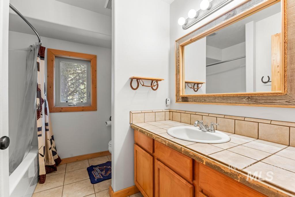 Bathroom with shower / bathtub combination with curtain, light tile patterned floors, and vanity
