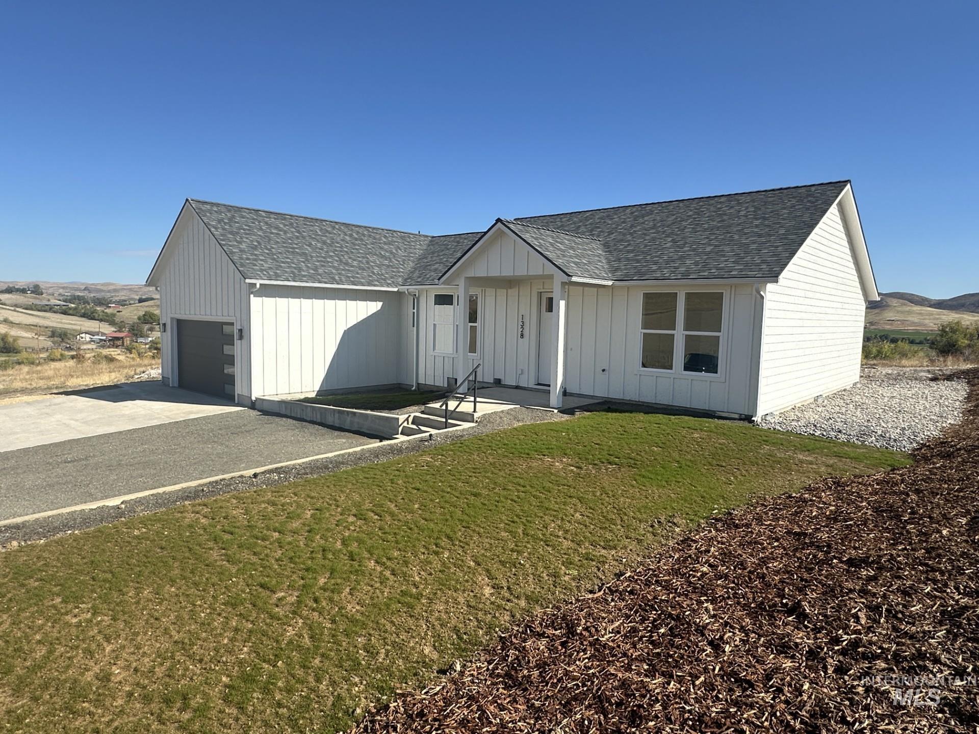 Modern inspired farmhouse with a shingled roof, a front lawn, driveway, and board and batten siding