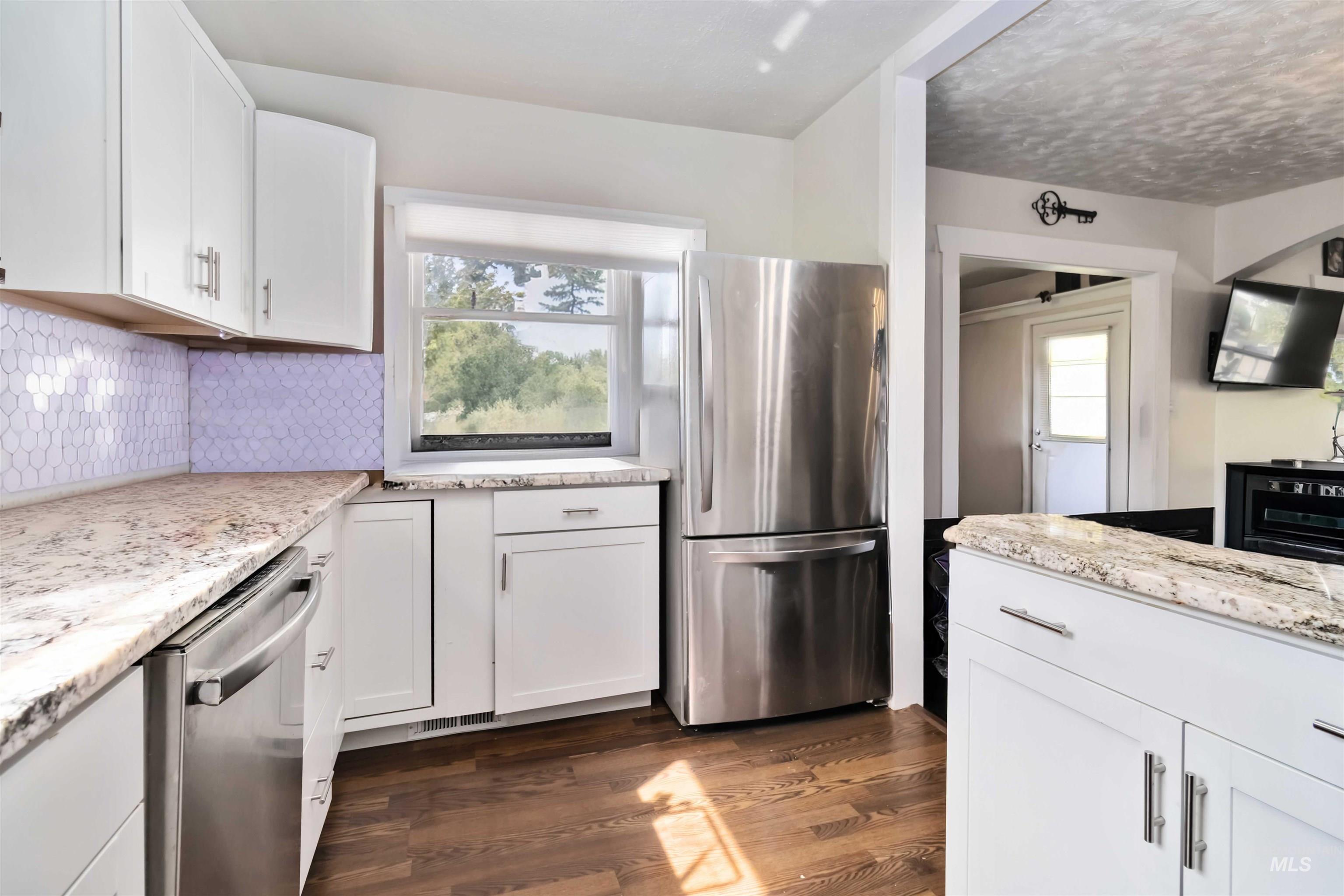 Kitchen featuring healthy amount of natural light, white cabinetry, and stainless steel appliances