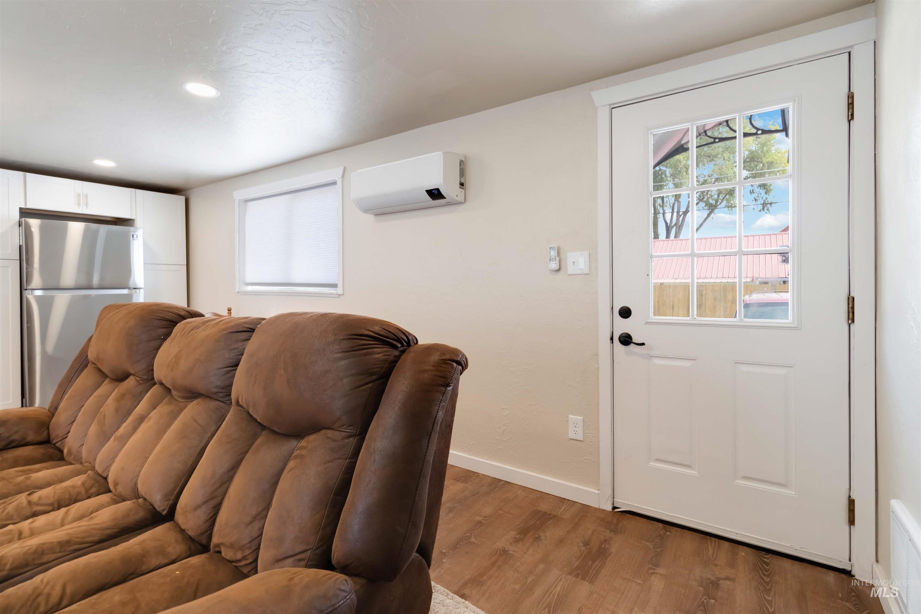 Living area with light wood-style flooring, healthy amount of natural light, recessed lighting, and a wall mounted AC
