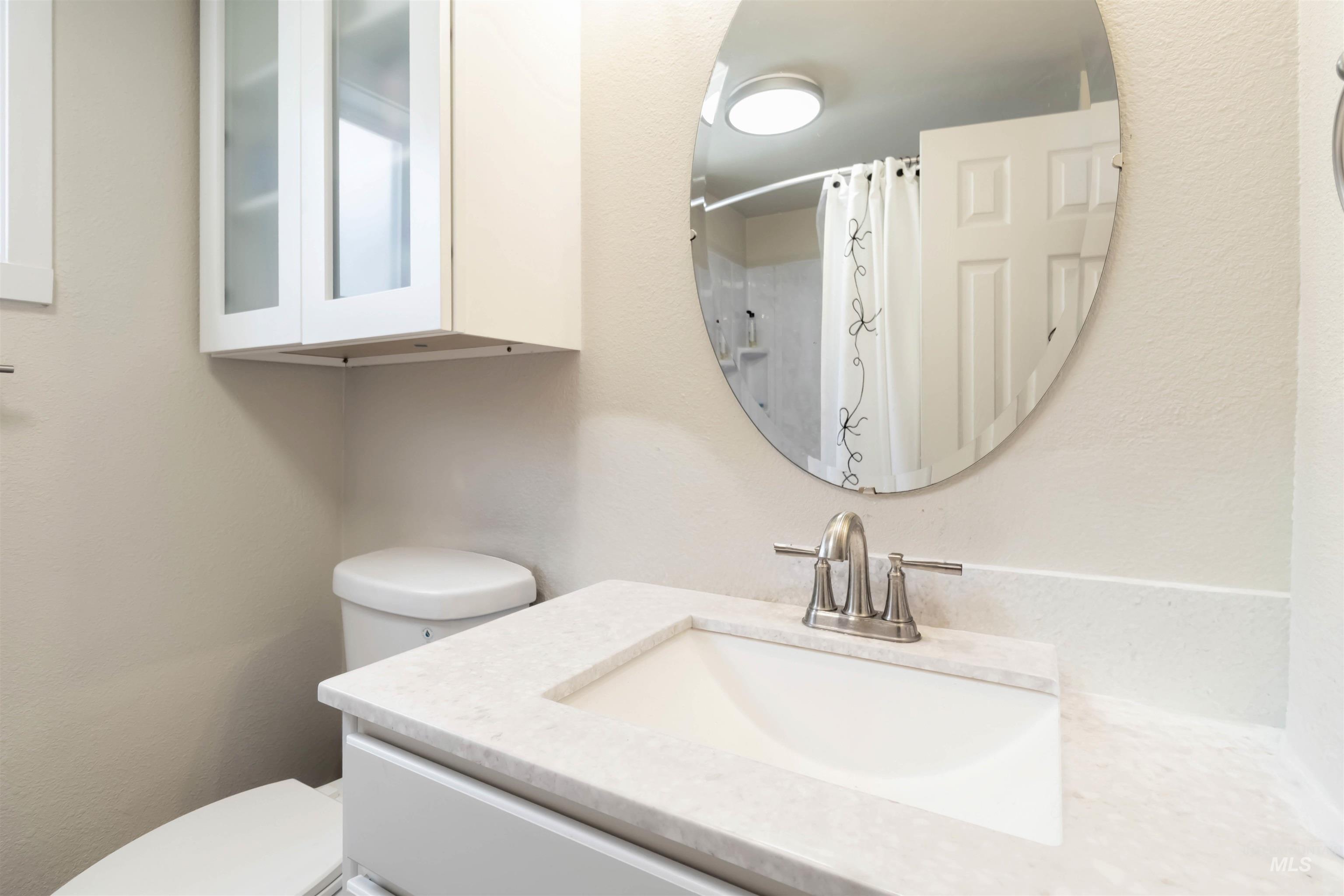 Bathroom with vanity, a shower with curtain, and a textured wall