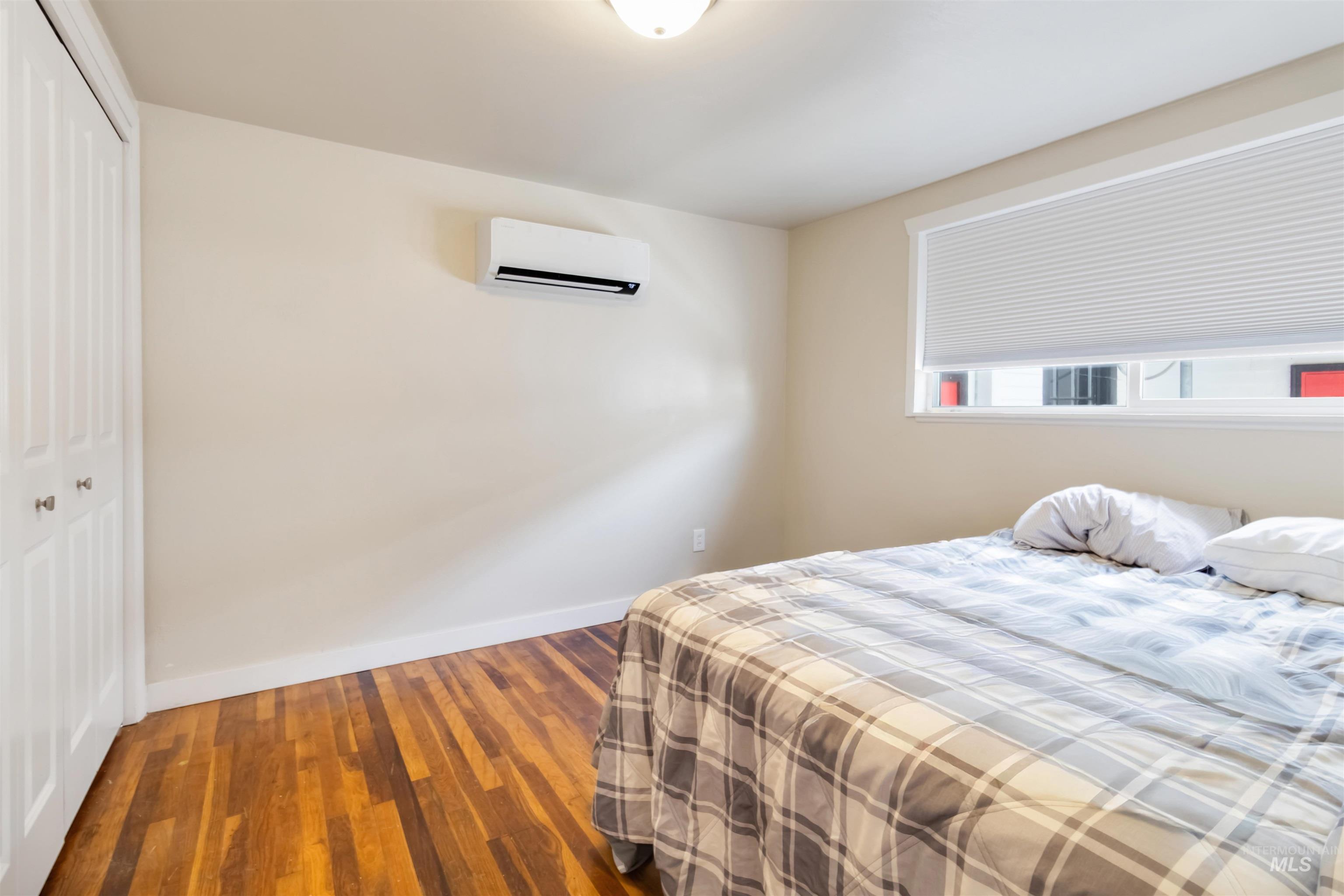 Bedroom with wood-type flooring, a closet, and an AC wall unit