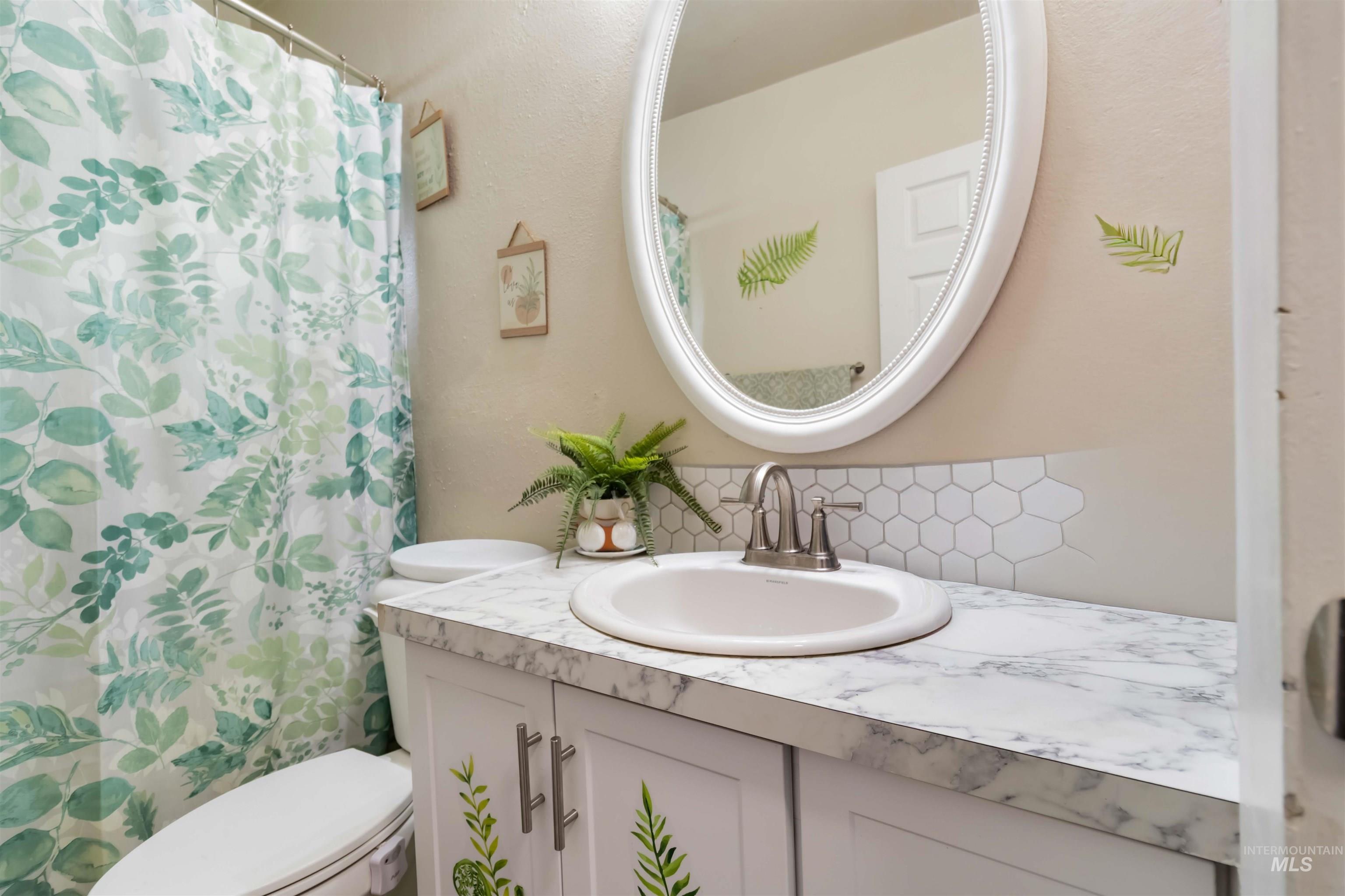 Full bathroom with tasteful backsplash, vanity, and a shower with curtain