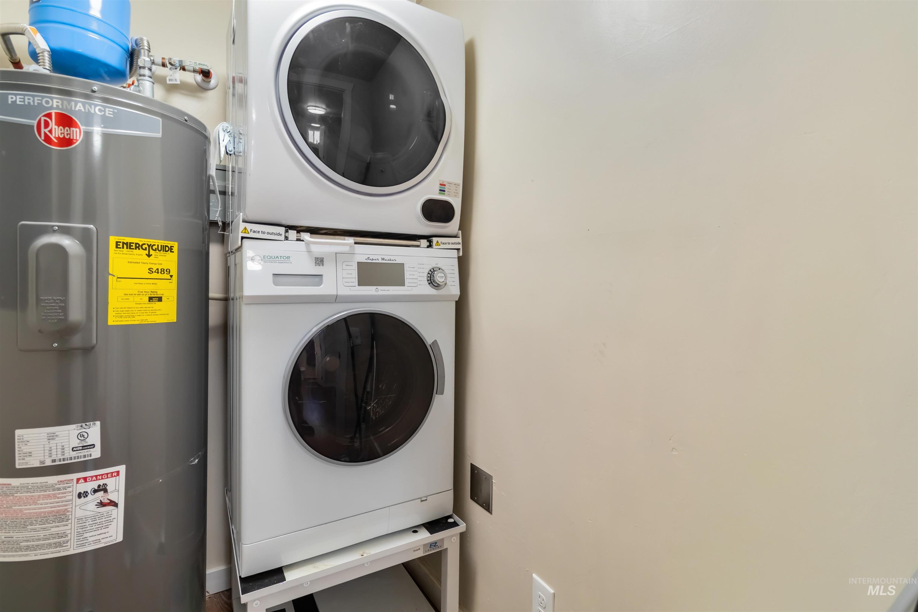 Laundry area with electric water heater and stacked washer and clothes dryer