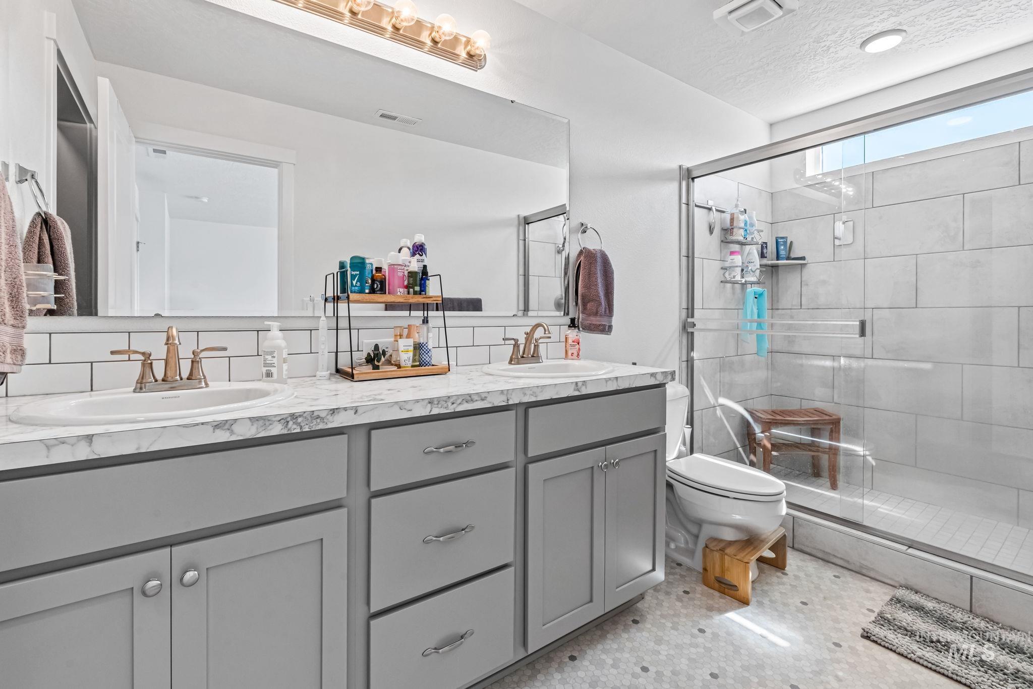 Full bathroom featuring double vanity and a stall shower