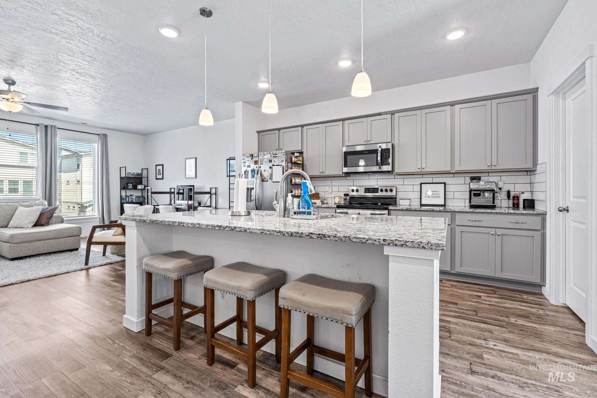 Kitchen featuring gray cabinetry, appliances with stainless steel finishes, decorative backsplash, recessed lighting, and a textured ceiling