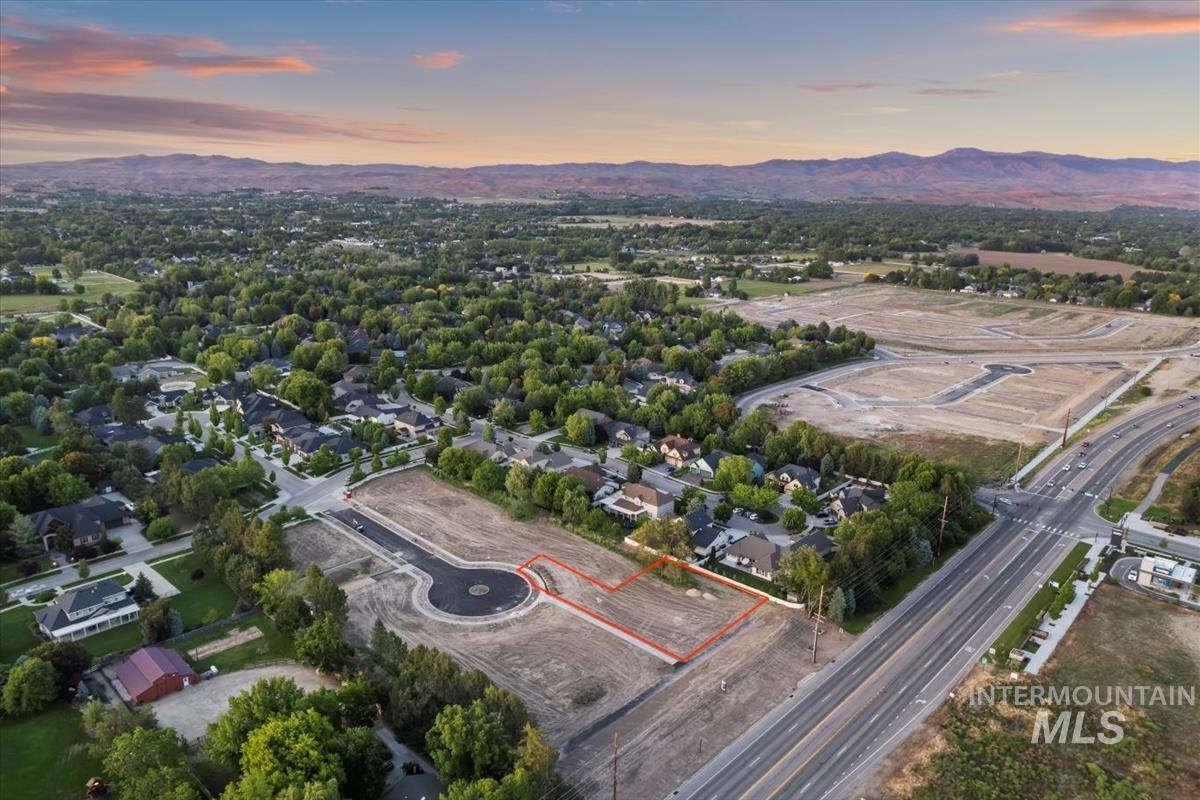 Aerial view of property and surrounding area with a mountain backdrop and property parcel outlined