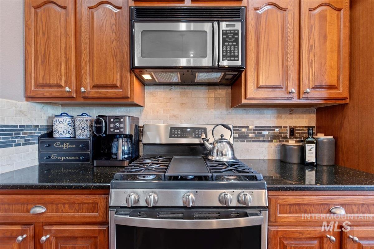 Kitchen featuring appliances with stainless steel finishes, brown cabinets, and decorative backsplash