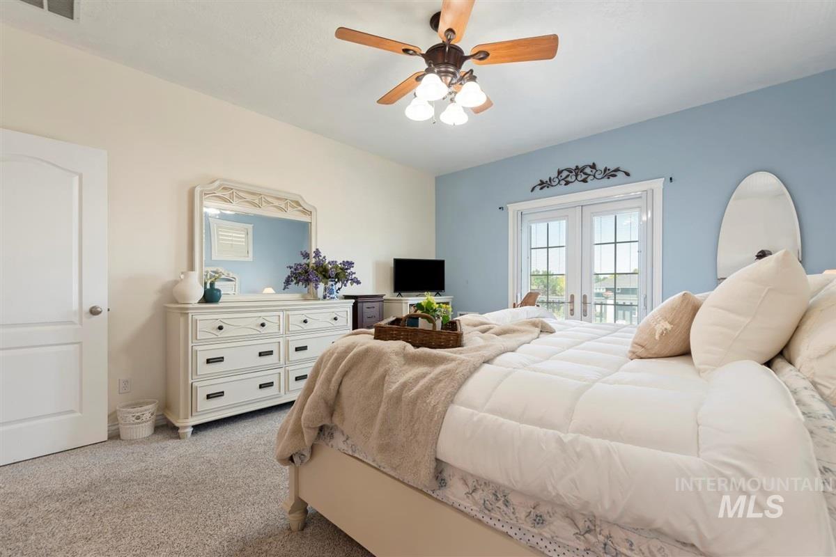Bedroom with access to exterior, light colored carpet, and a ceiling fan