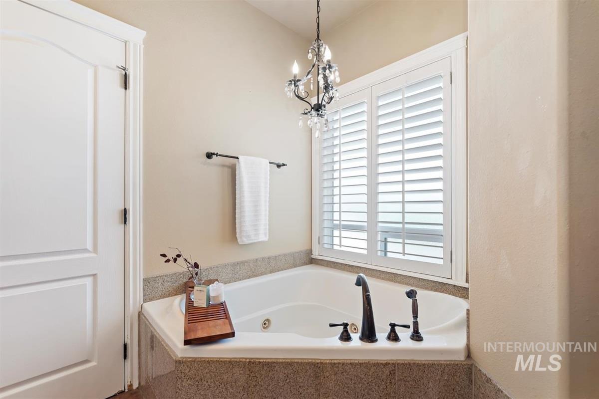 Bathroom featuring a jetted tub and a chandelier
