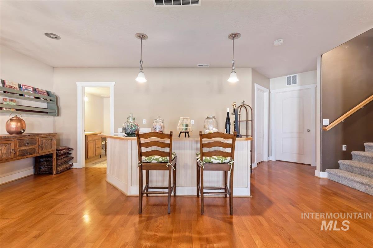 Wet Bar featuring light wood-style flooring, a breakfast bar area, and hanging light fixtures