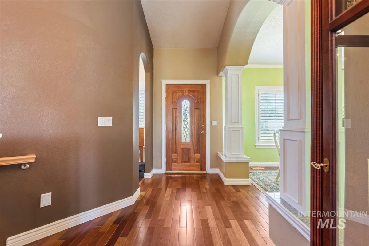 Entrance foyer featuring arched walkways, light wood-type flooring, and ornate columns