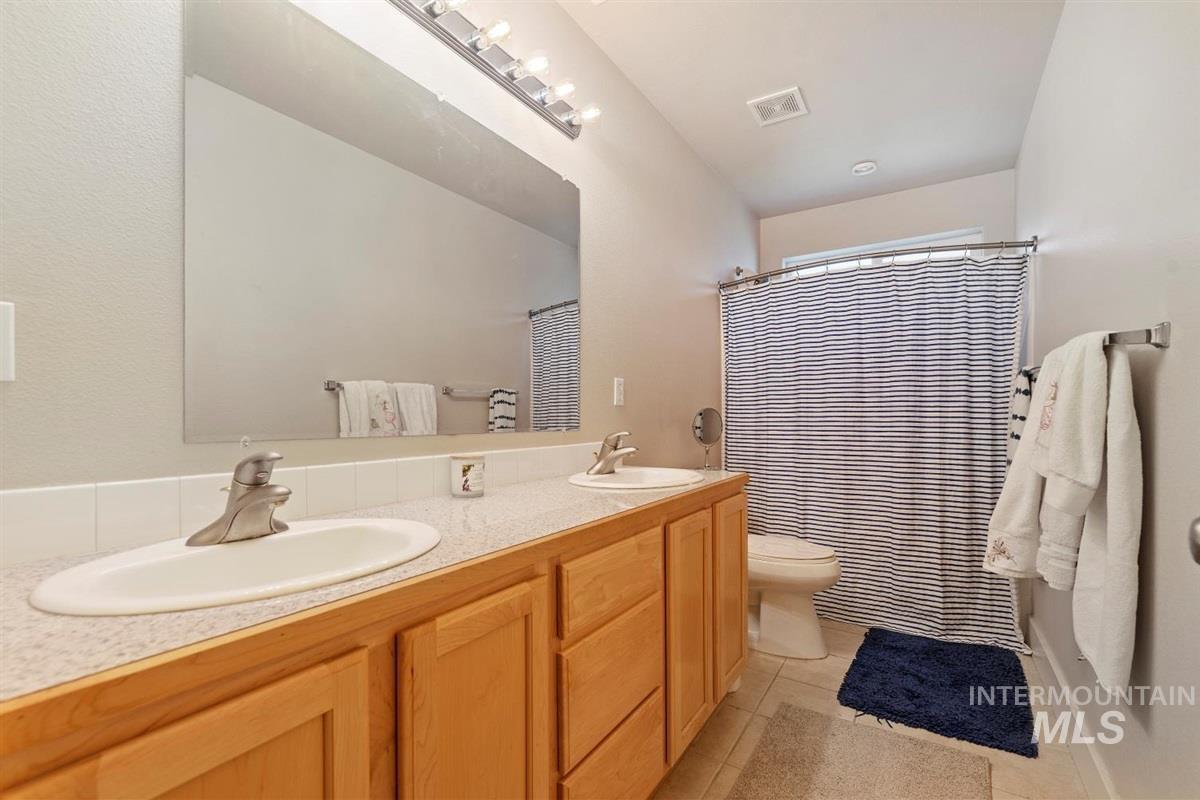 Full bathroom featuring tile patterned floors, double vanity, and curtained shower