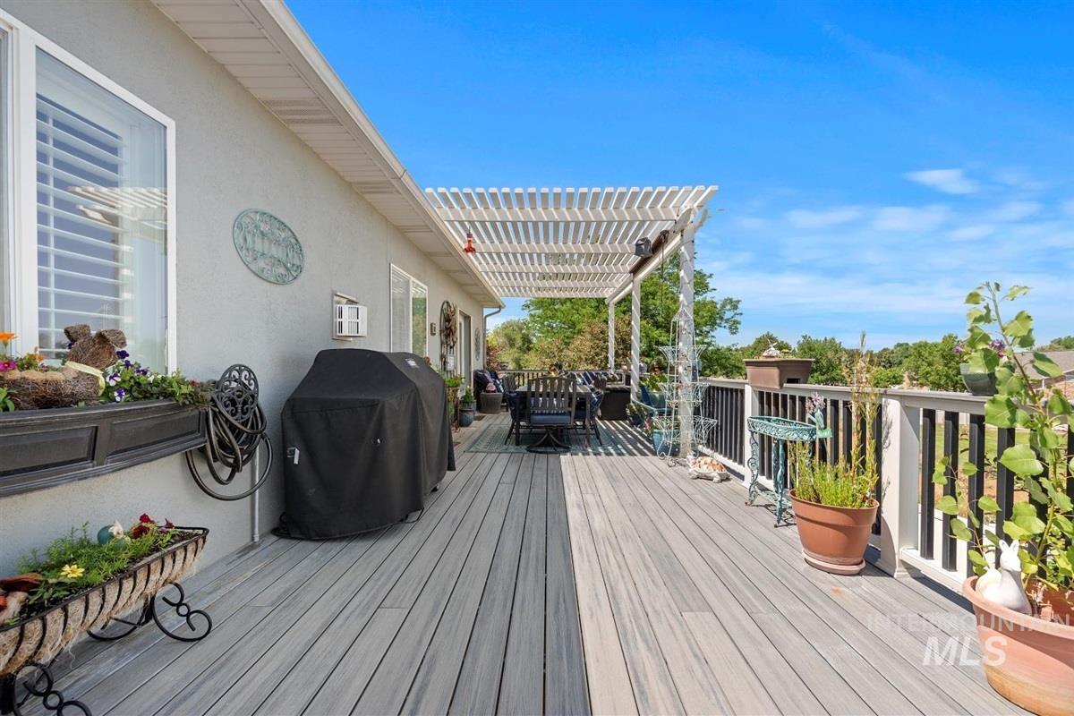 Wooden deck with outdoor dining space, area for grilling, and a pergola