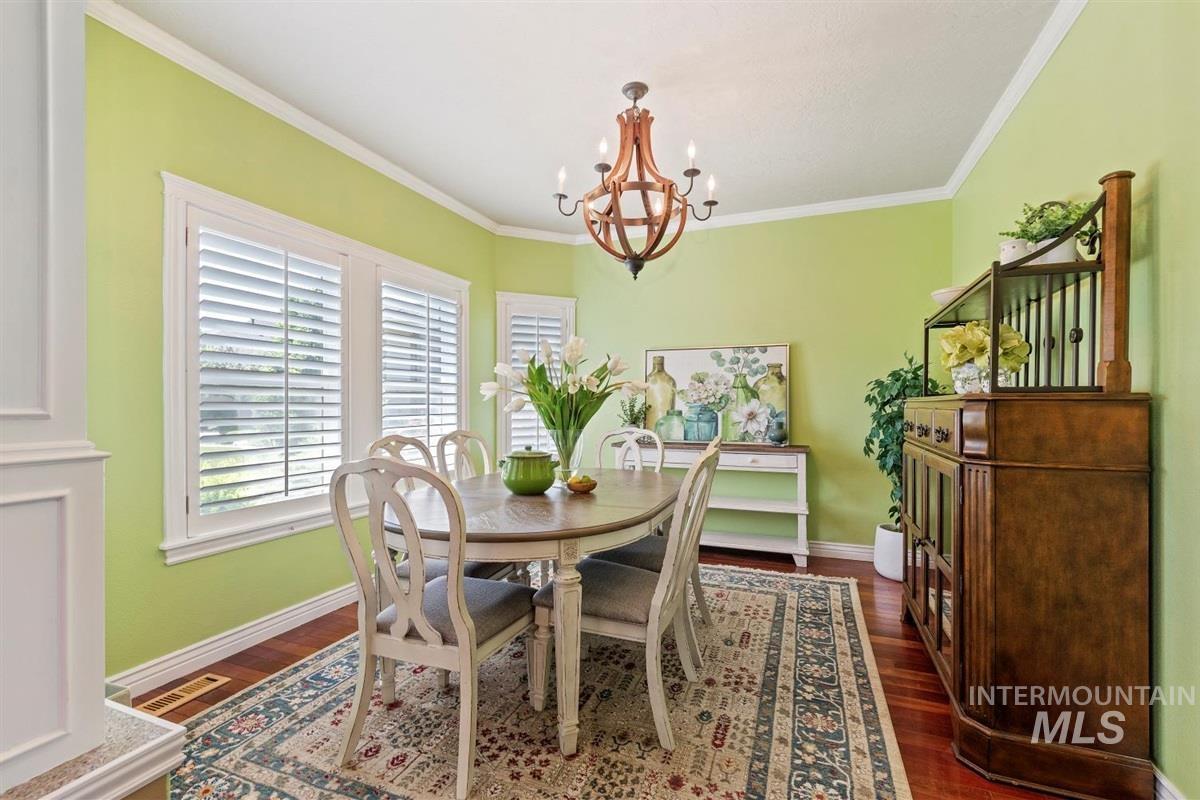 Dining area featuring a chandelier, dark wood finished floors, and crown molding
