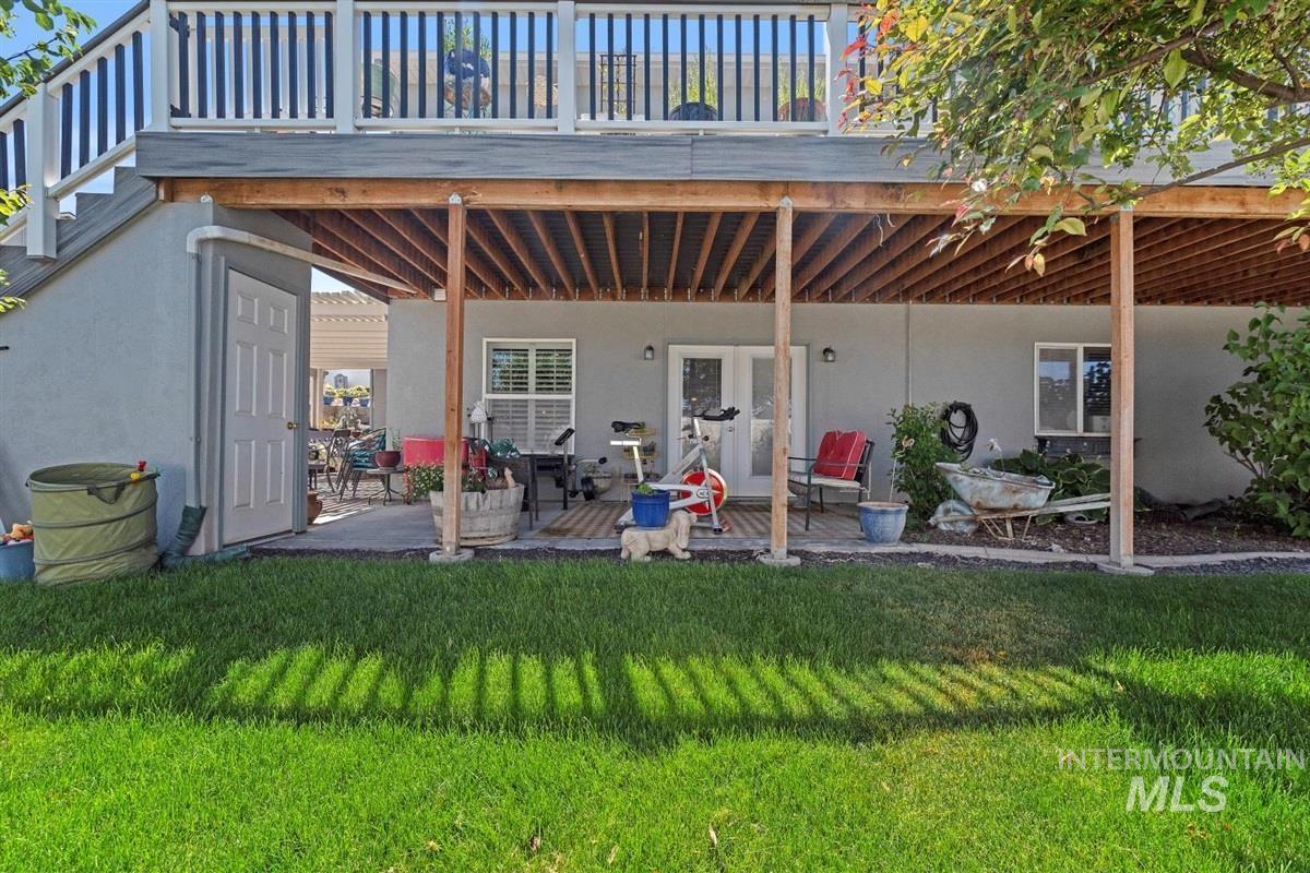 Rear view of property featuring stucco siding, a yard, a patio, and a wooden deck