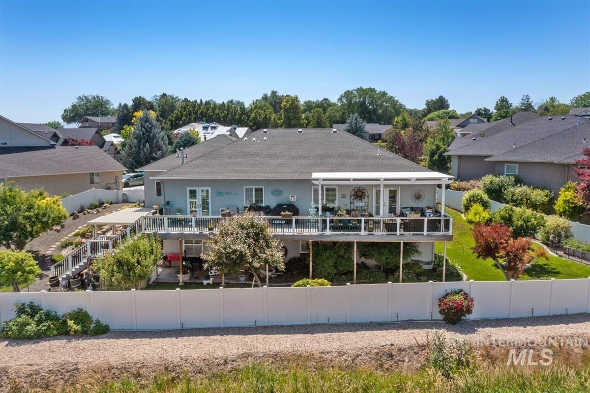 Rear view of house featuring a fenced backyard, a shingled roof, a residential view, and a deck