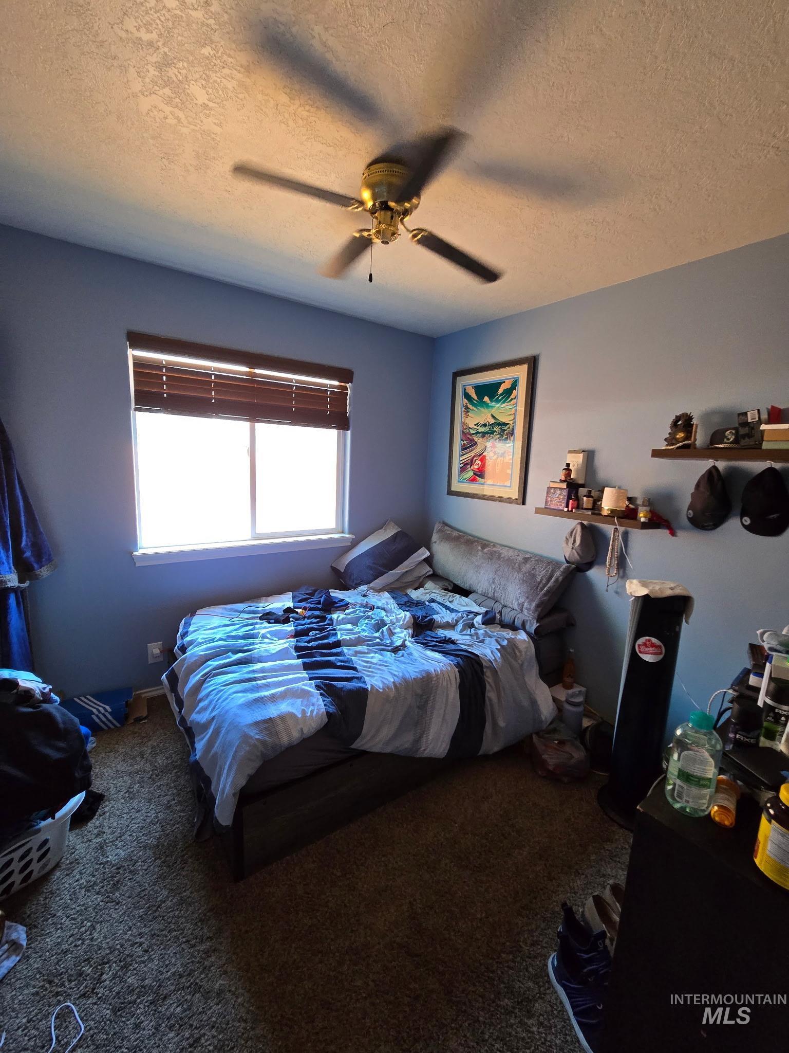 Carpeted bedroom with a textured ceiling and ceiling fan
