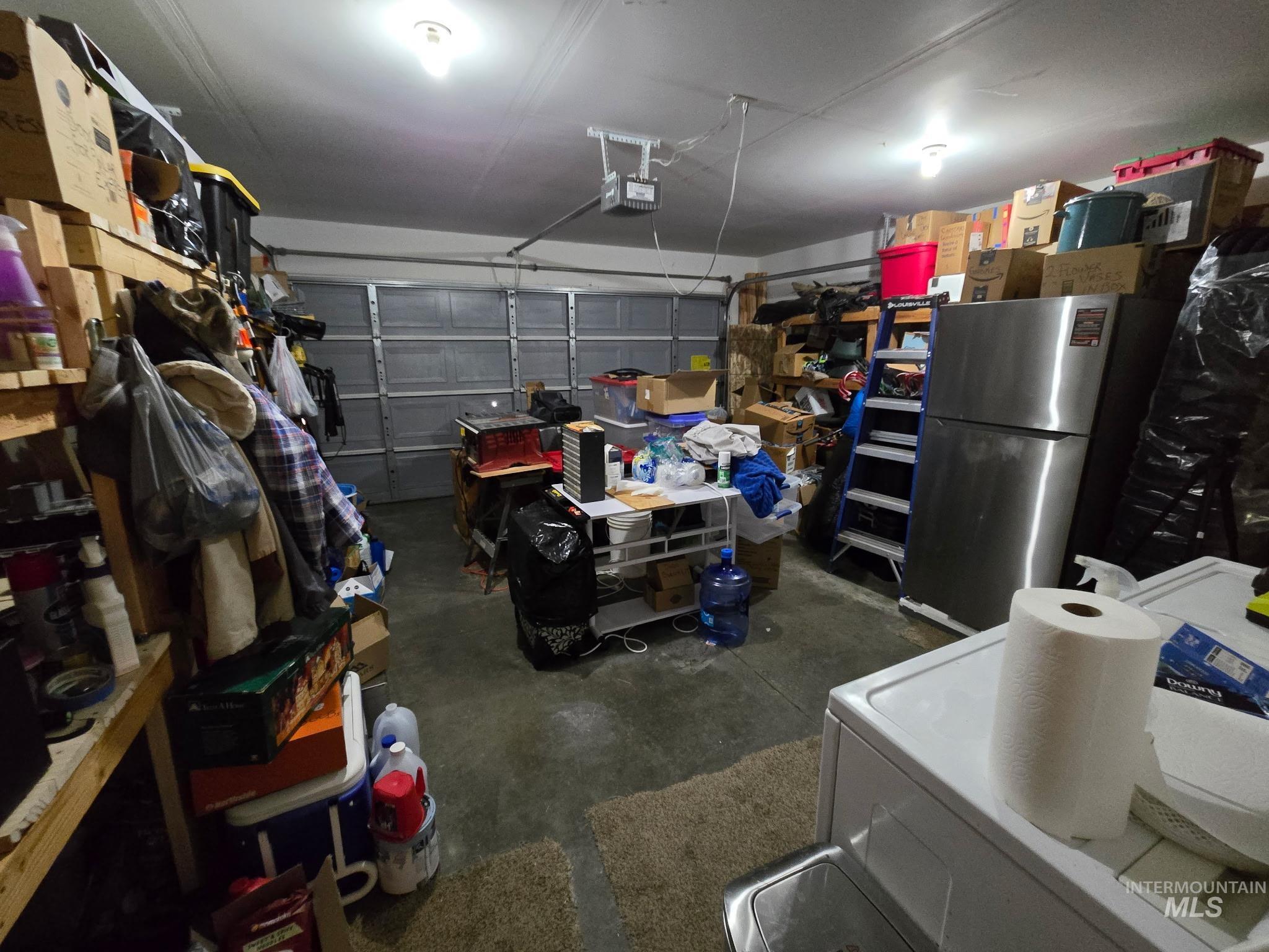 Garage featuring freestanding refrigerator, washer / dryer, and a garage door opener