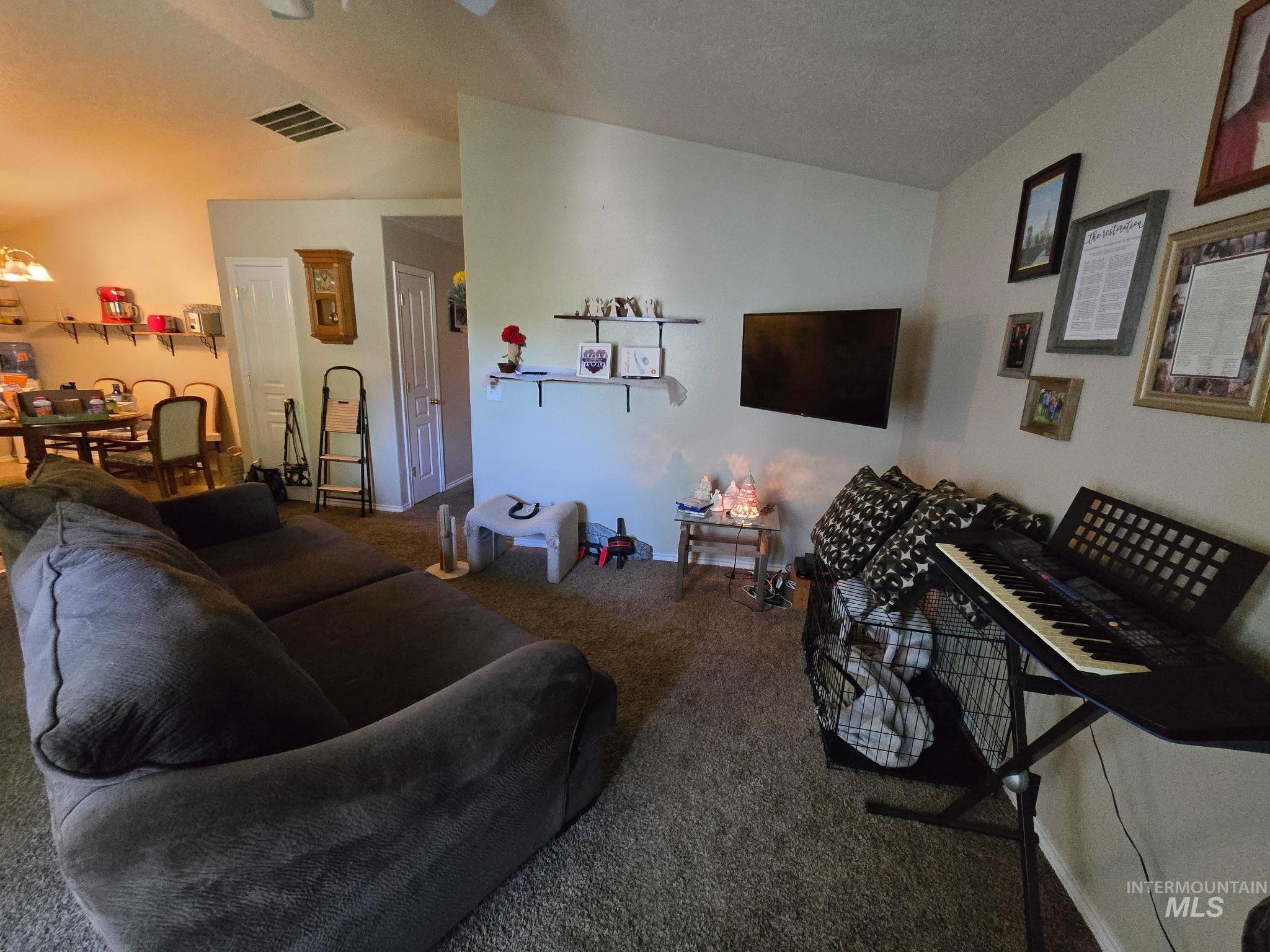 Carpeted living area with vaulted ceiling, a chandelier, and a textured ceiling