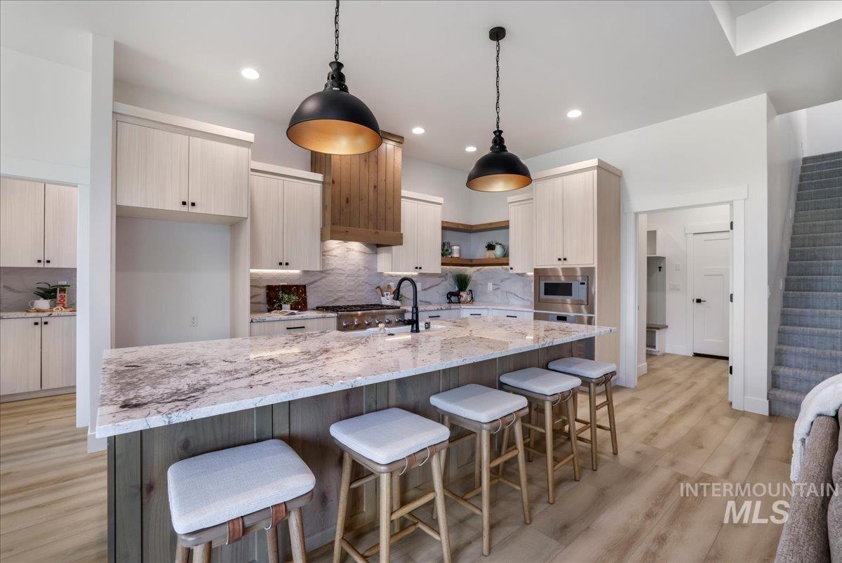 Kitchen with stainless steel microwave, tasteful backsplash, light wood-type flooring, open shelves, and recessed lighting