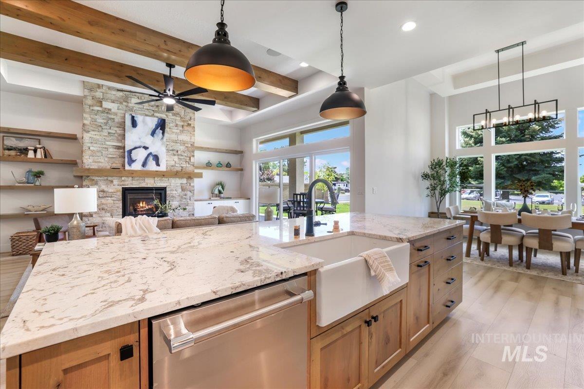 Kitchen featuring dishwasher, beam ceiling, a ceiling fan, light wood-style flooring, and a stone fireplace