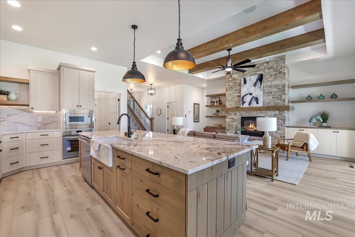 Kitchen featuring open shelves, appliances with stainless steel finishes, light wood-style flooring, backsplash, and a stone fireplace