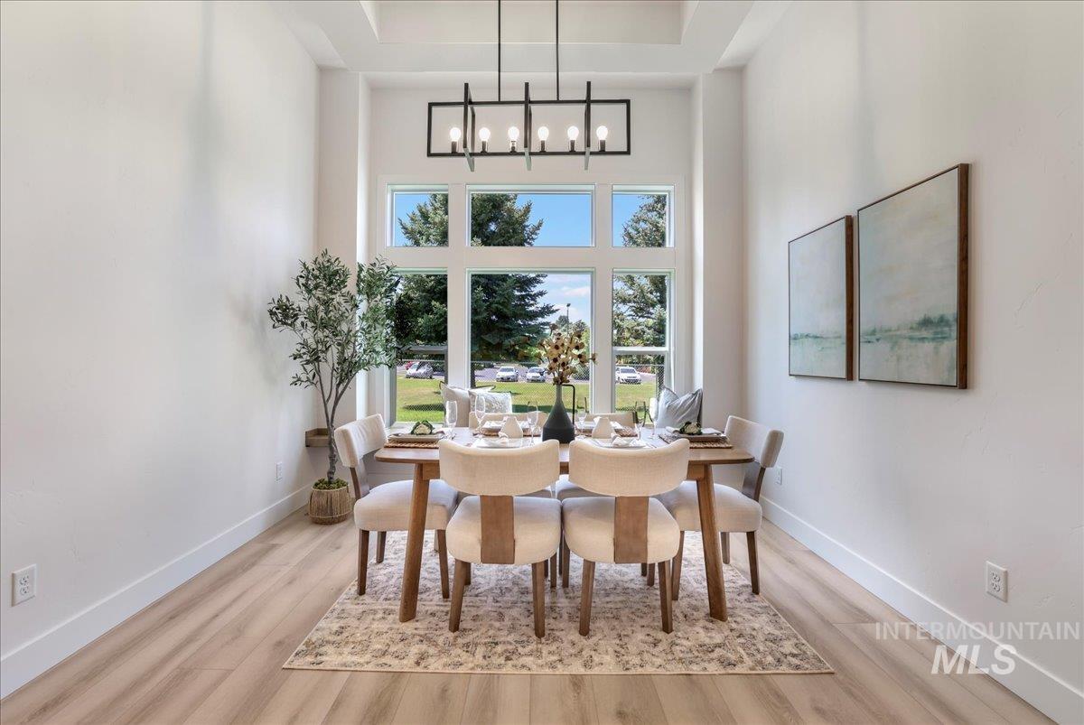 Dining area with a chandelier, a towering ceiling, wood finished floors, and a tray ceiling