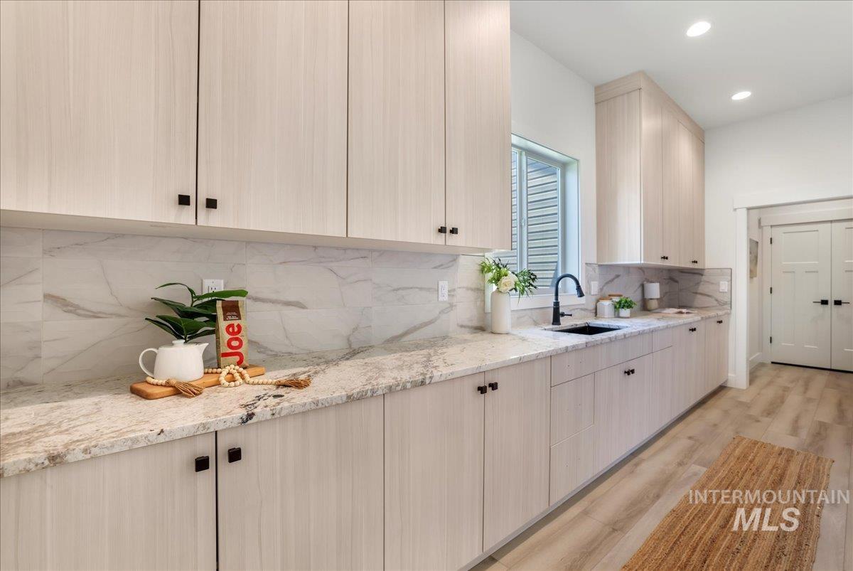 Kitchen featuring light wood-style flooring, tasteful backsplash, light stone countertops, and recessed lighting