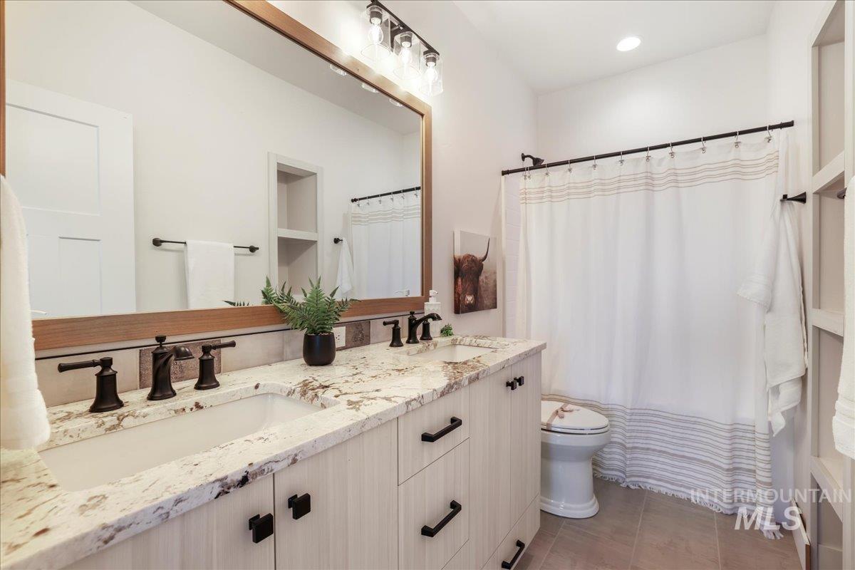 Full bath with double vanity, tile patterned flooring, and curtained shower