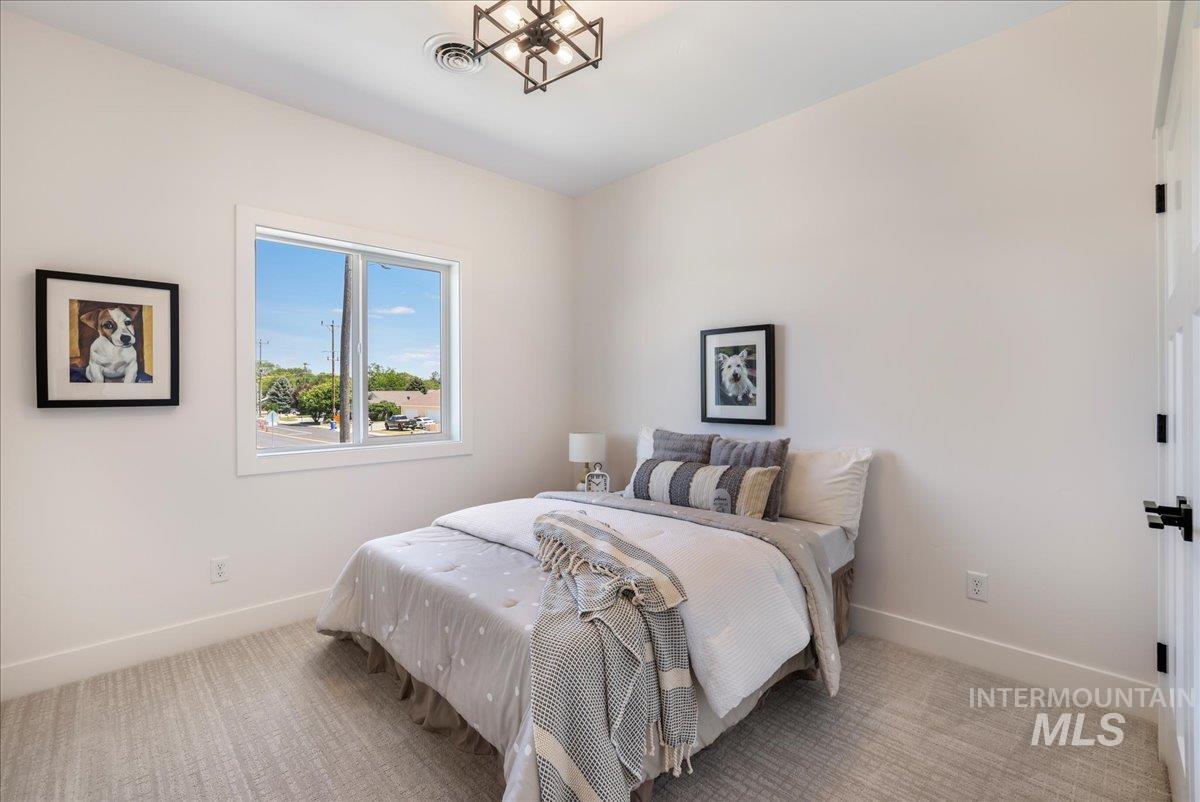 Bedroom featuring light carpet and a chandelier