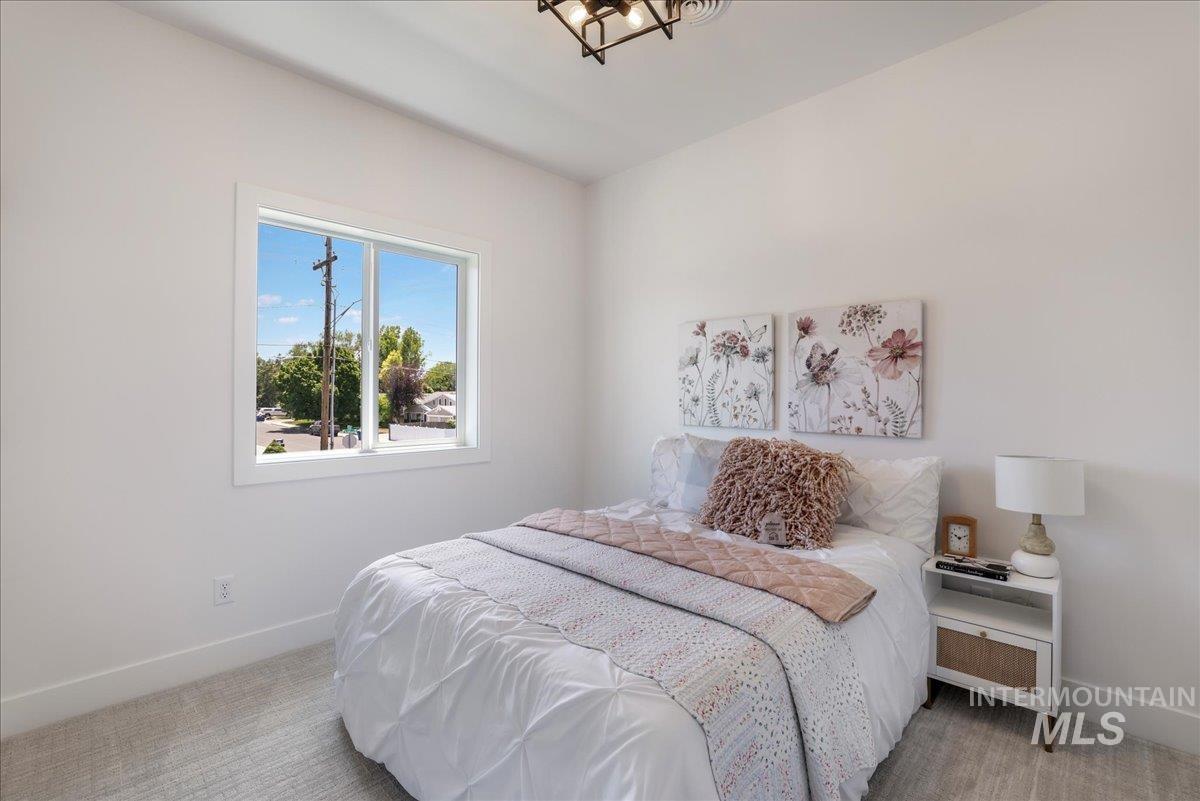 Bedroom with light colored carpet and a chandelier