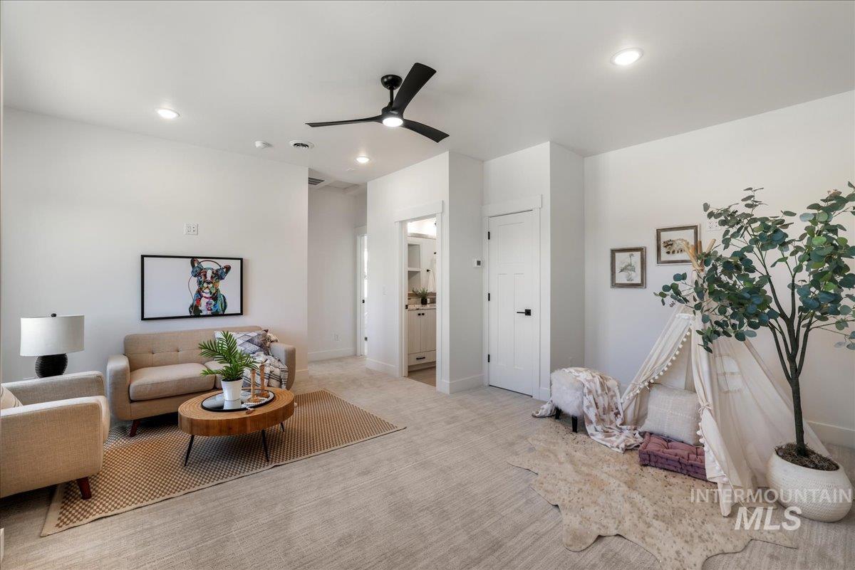Carpeted living room with a ceiling fan and recessed lighting