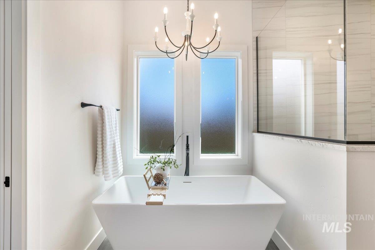 Bathroom with a soaking tub, plenty of natural light, and a chandelier
