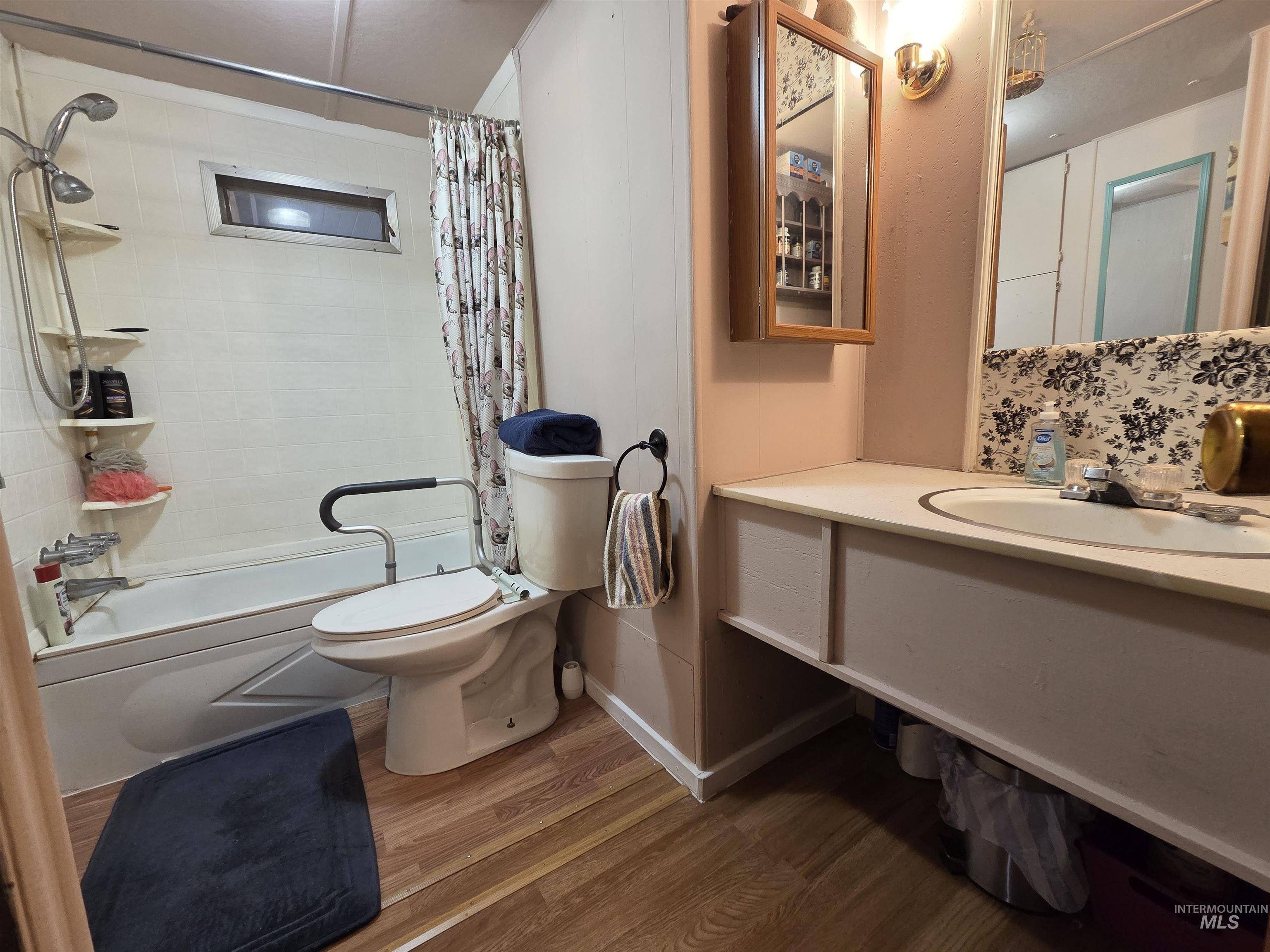 Full bath featuring dark wood-style flooring, vanity, and shower / bath combination with curtain