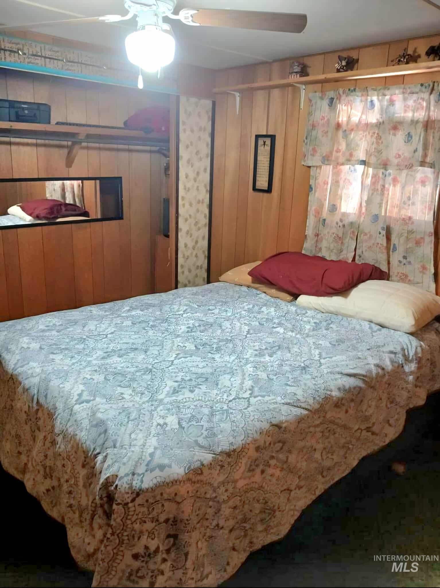 Bedroom featuring a ceiling fan and wood walls