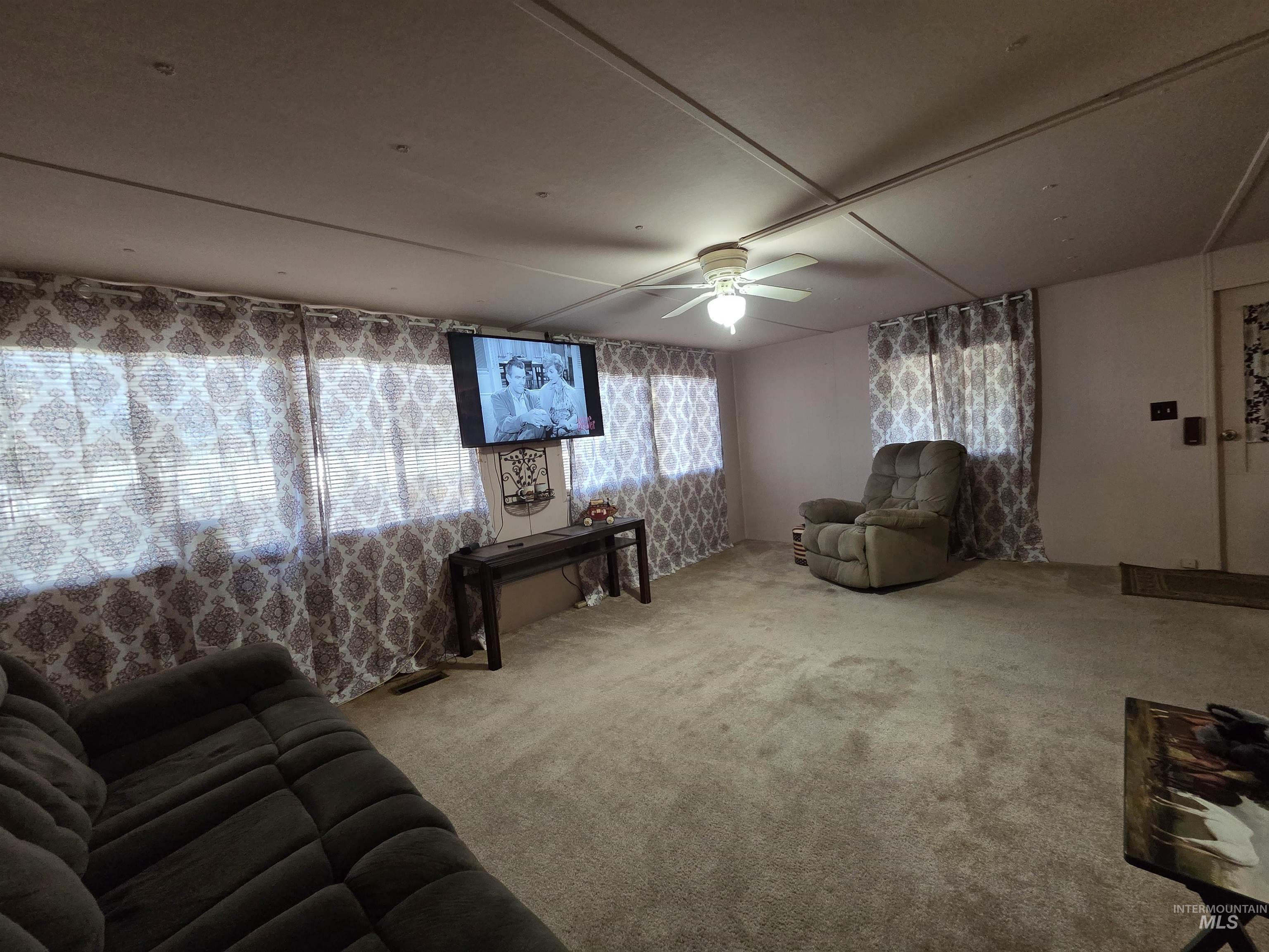 Living area featuring carpet floors and ceiling fan
