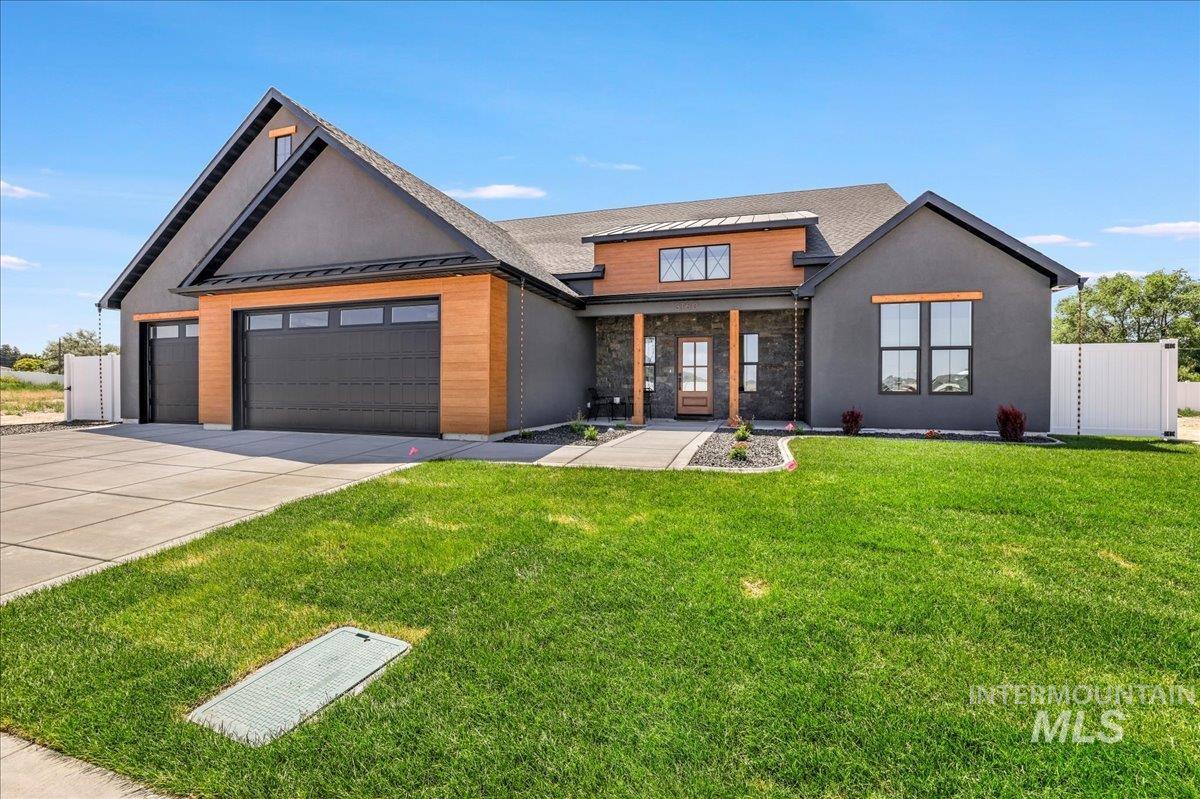 View of front facade featuring a standing seam roof, concrete driveway, an attached garage, a metal roof, and stone siding