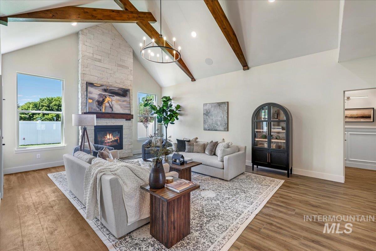 Living area with high vaulted ceiling, beamed ceiling, a stone fireplace, wood finished floors, and recessed lighting