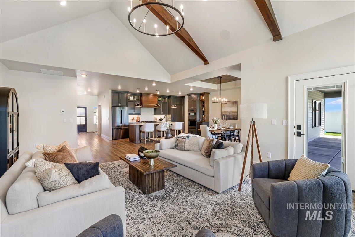 Living area featuring a chandelier, high vaulted ceiling, beam ceiling, wood finished floors, and recessed lighting