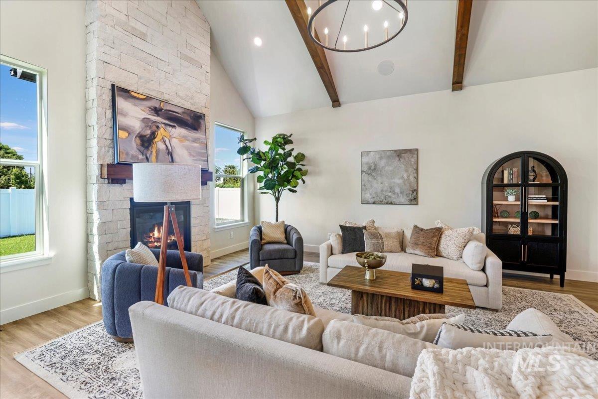 Living area with wood finished floors, beam ceiling, a fireplace, a chandelier, and high vaulted ceiling