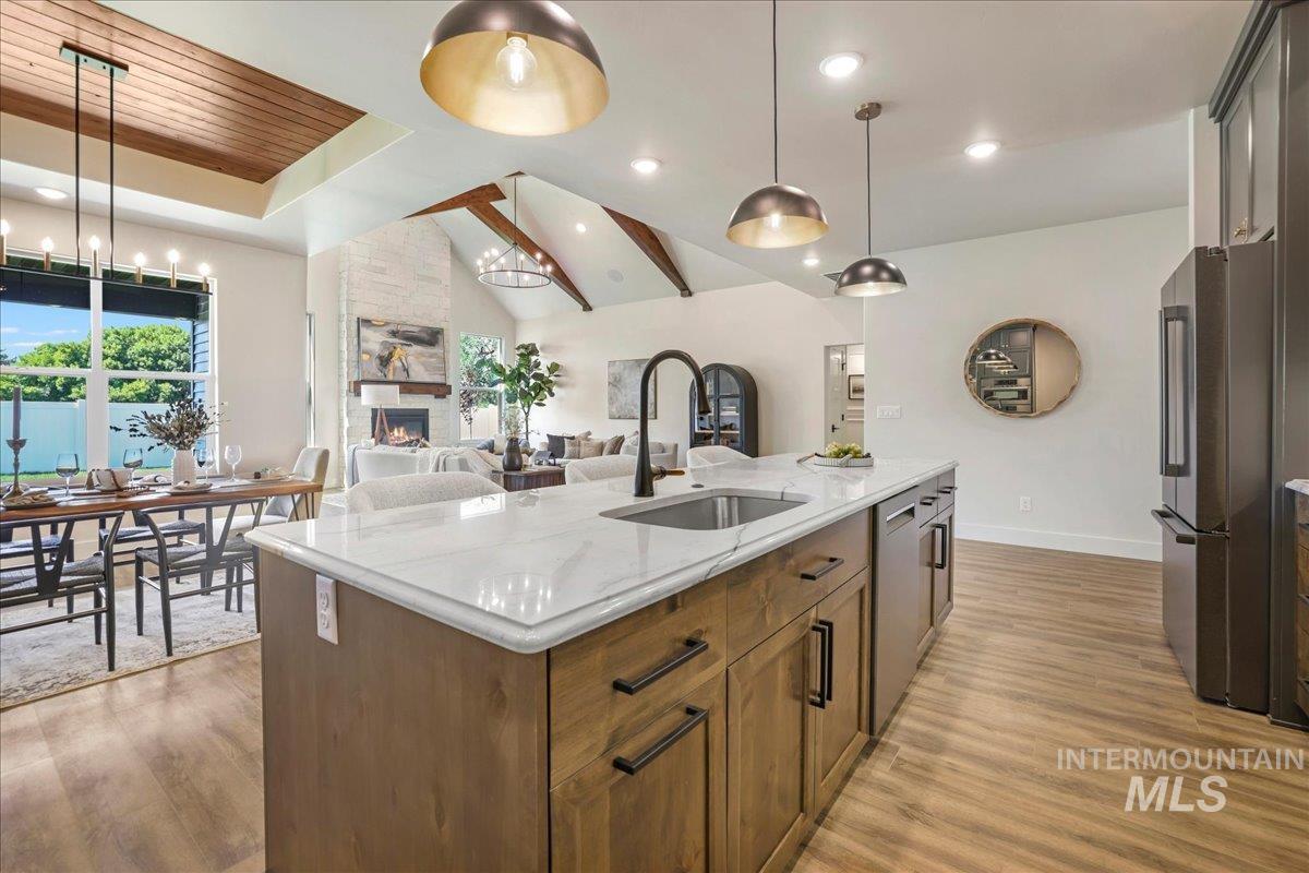 Kitchen with appliances with stainless steel finishes, light wood-style flooring, a fireplace, decorative light fixtures, and recessed lighting