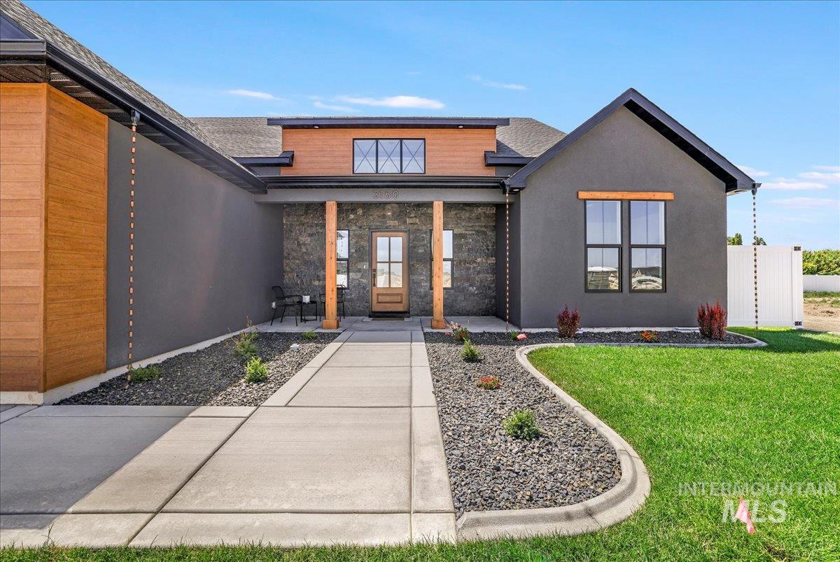 Property entrance featuring a lawn, stucco siding, a porch, a shingled roof, and stone siding